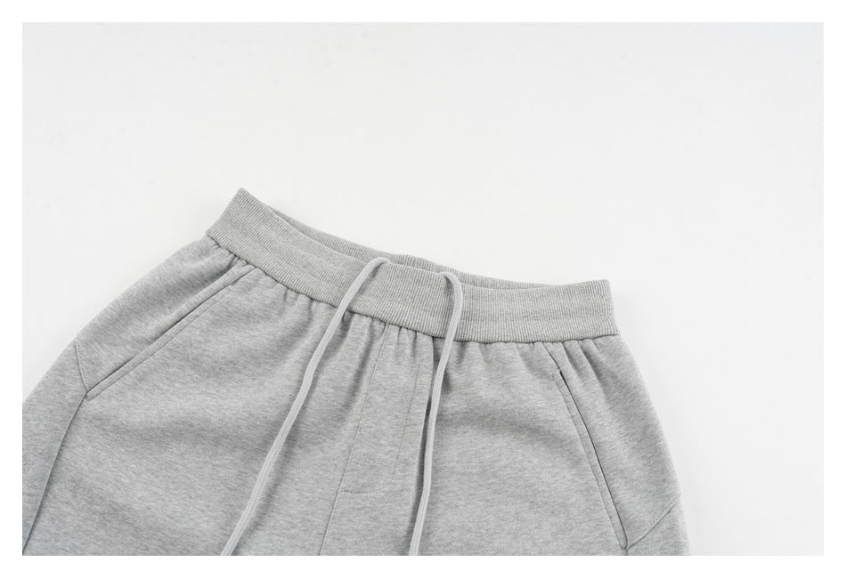 Close-up of light gray sweatpants waistband, drawstrings, and upper front with angled pockets.