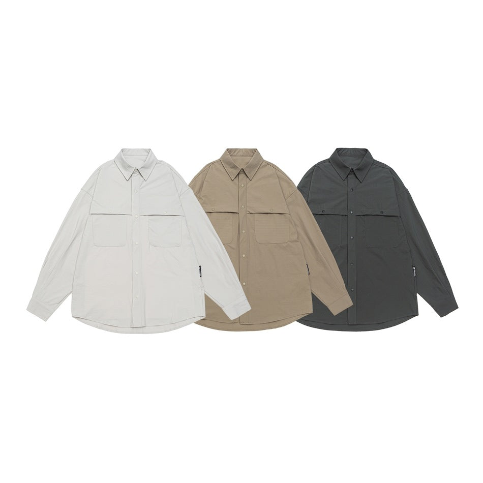Three oversized button-up shirts with flap chest pockets shown in light gray, taupe, and charcoal.