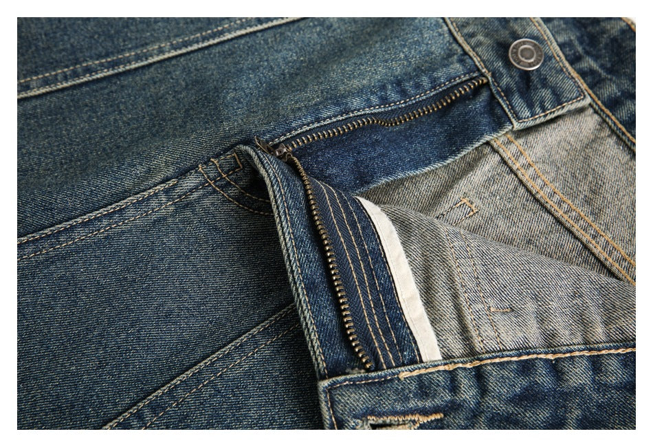 Close-up of blue denim trousers with the fly unfastened, showing the zipper and inner fastening.
