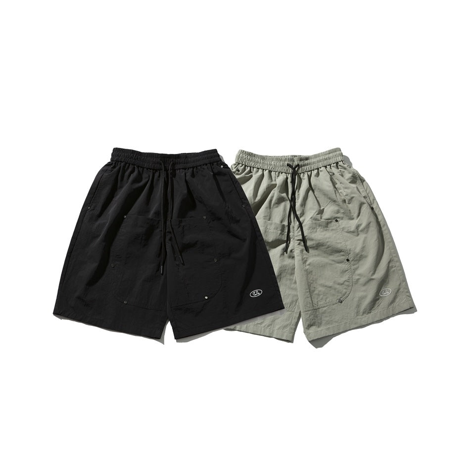 Two utility shorts displayed together in black and light taupe, each with a drawstring waist and patch pockets.