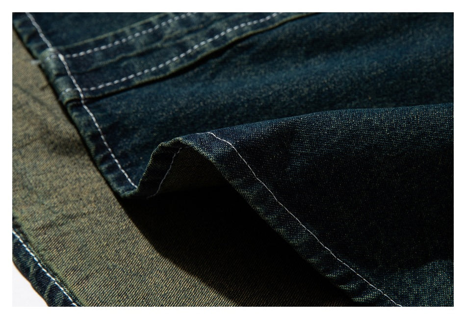 Close-up of dark indigo-green garment fabric folded to show a stitched seam and edge.