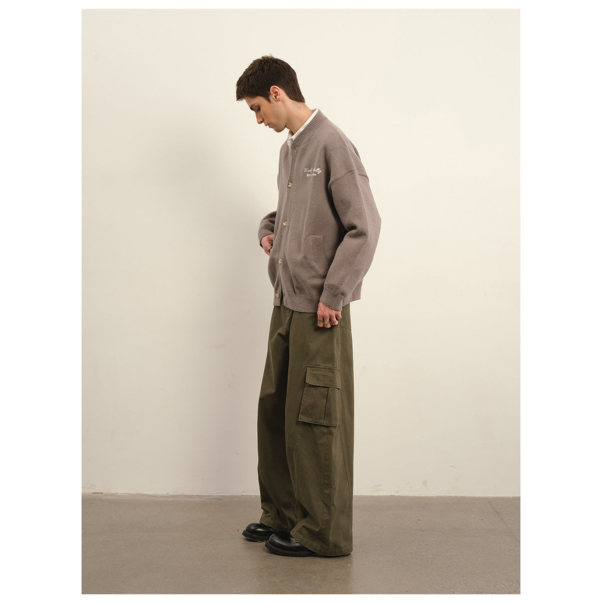 Side view of a model wearing a taupe button-front cardigan and loose olive cargo trousers.