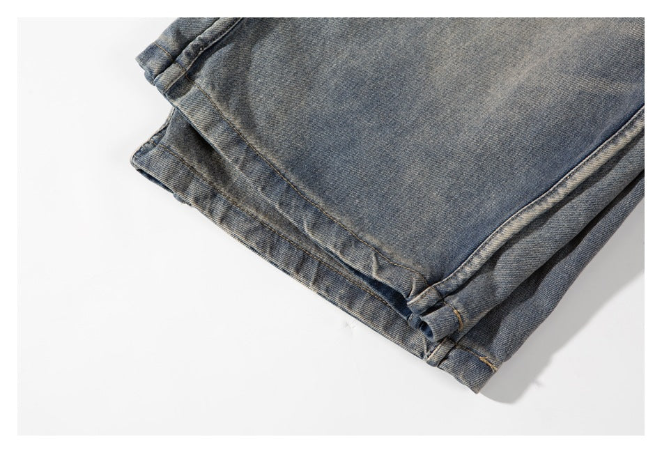 Close-up of the folded hem and cuff of faded blue-gray jeans laid flat.
