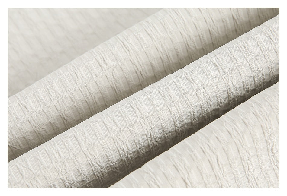 Close-up of ivory textured fabric arranged in soft folds.