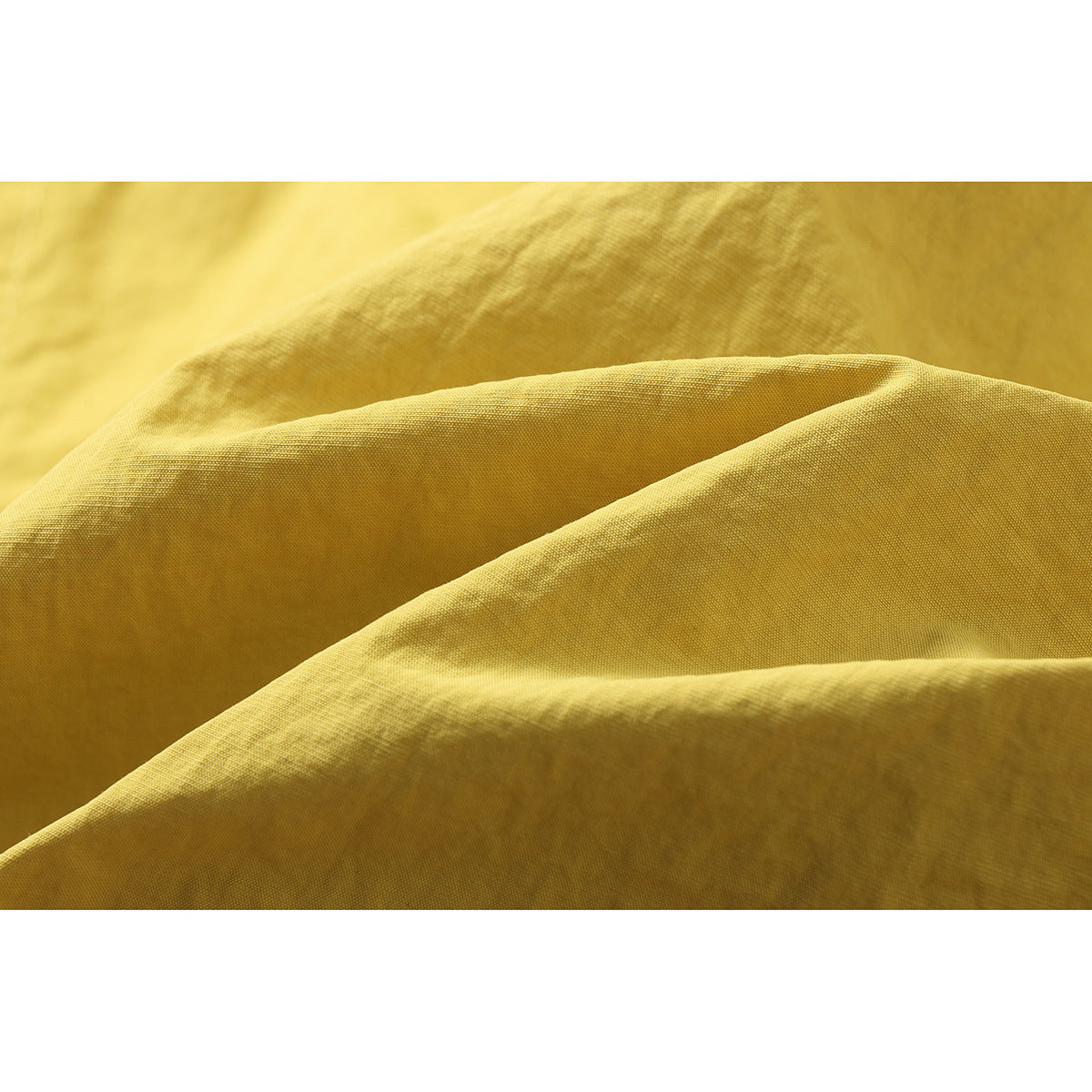 Close-up of yellow jacket fabric draped into folds, showing its surface texture.