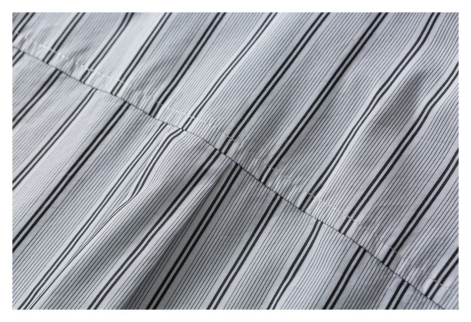 Close-up of striped light gray fabric showing a curved stitched seam and gathered folds.