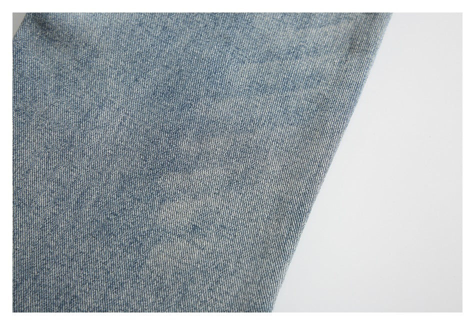 Close-up of mottled light blue denim showing its faded wash and diagonal weave.