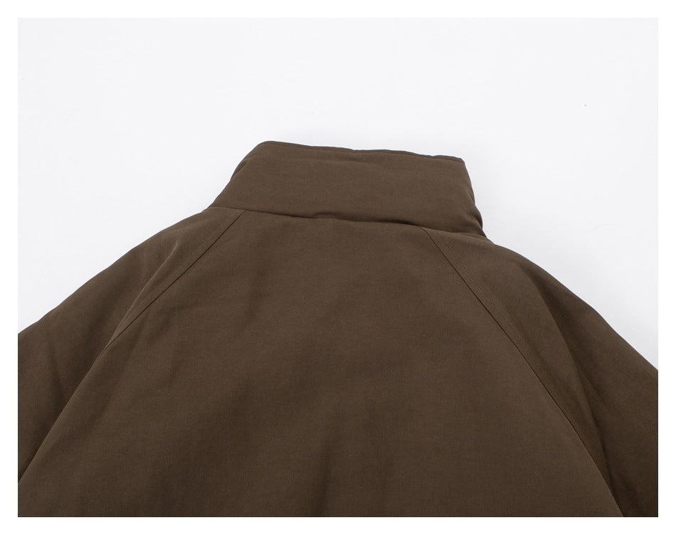 Cropped rear view of a brown jacket with a raised collar and angled raglan seams.
