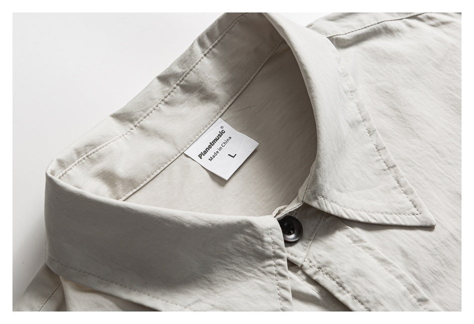 Close-up of a light gray button-up shirt collar, dark button, and inner brand and size label.