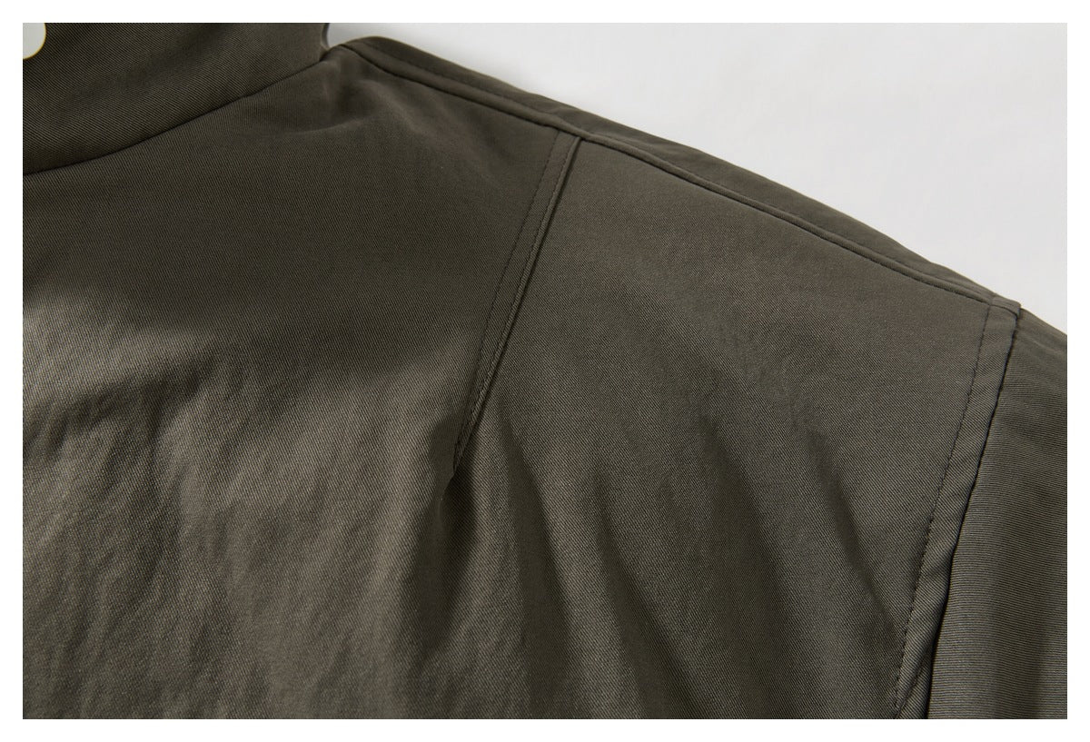 Close-up of the dark olive jacket's shoulder seam and sleeve construction.