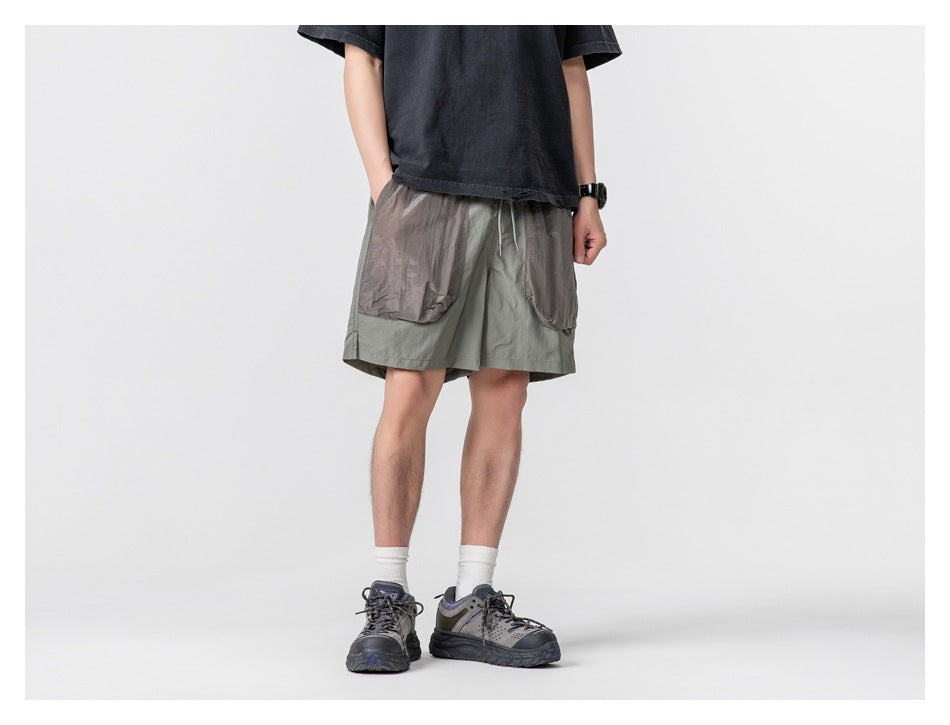 Front view of a person wearing sage gray shorts with oversized contrasting front pockets.