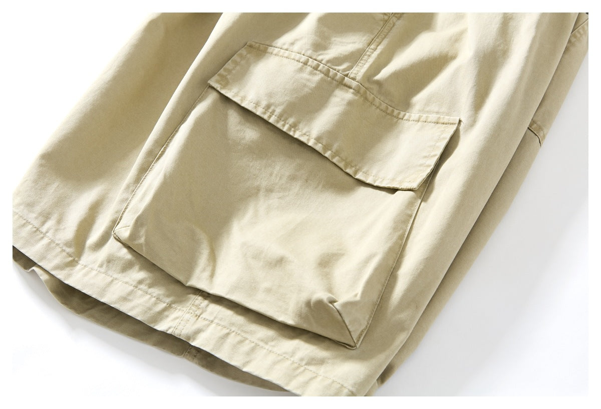 Close-up of a large flap cargo pocket on beige trousers, with the leg hem visible.