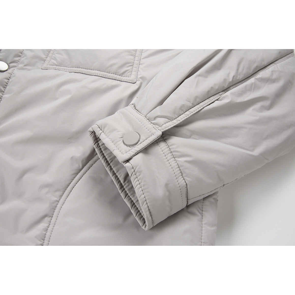 Close-up of a light gray jacket sleeve cuff with an adjustable snap tab and visible stitching.