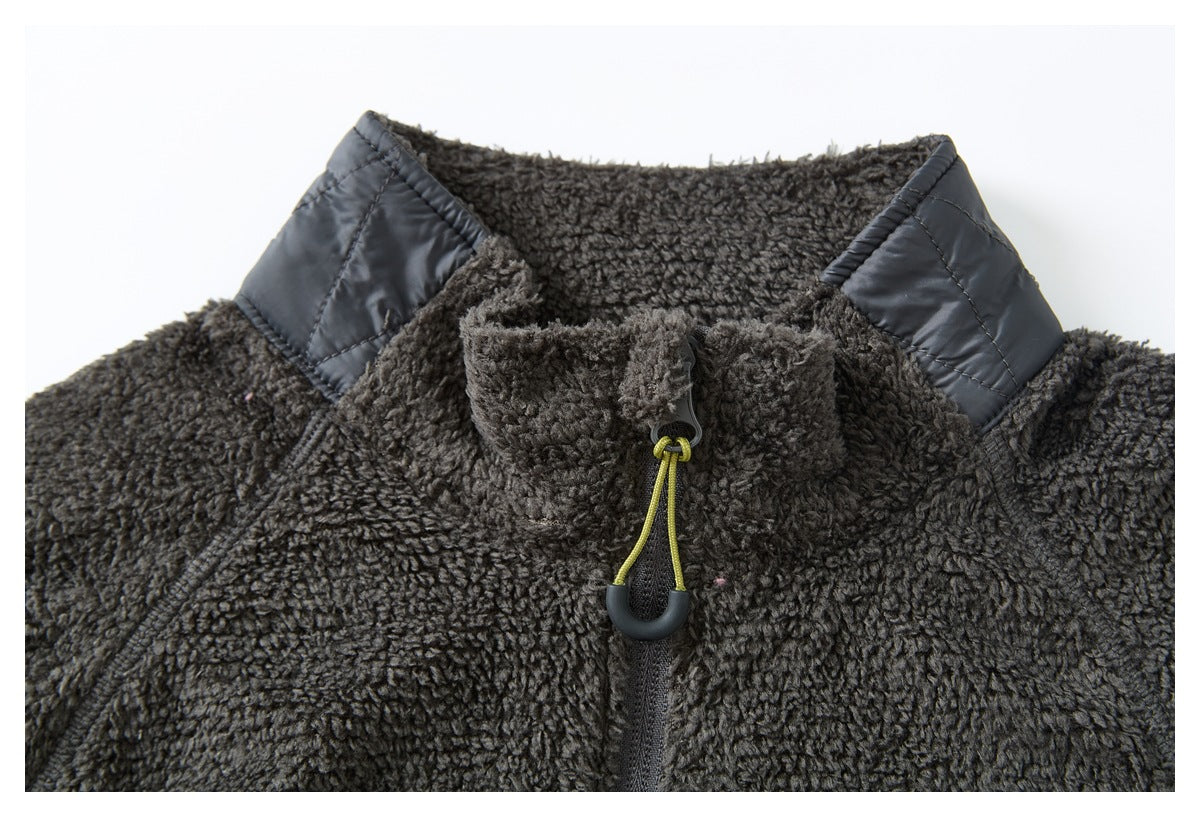 Close-up of a charcoal fleece jacket collar with a quilted dark shoulder panel and front zipper pull.