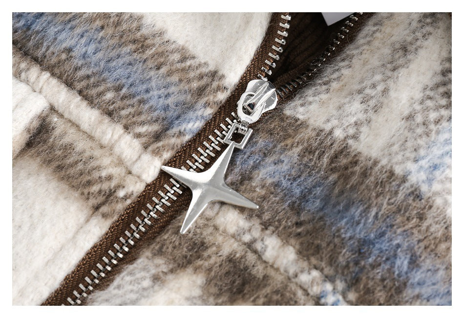 Close-up of a silver star-shaped zipper pull on a brown zipper over cream, gray, and blue plaid fabric.