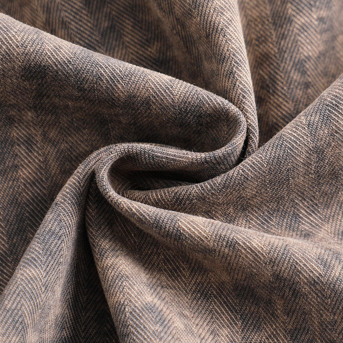 Macro view of brown-gray herringbone-patterned fabric folded to show its weave and texture.