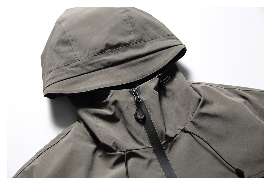 Close-up of a charcoal-gray hooded jacket showing the hood, high collar, front zipper and drawcords.