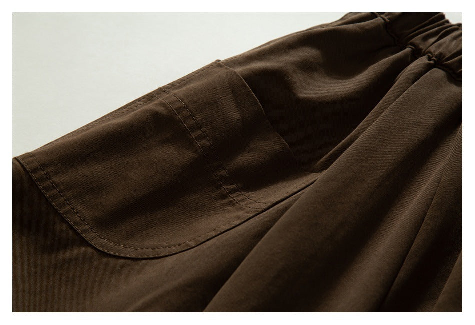 Close-up of a large stitched patch pocket on dark brown trousers.