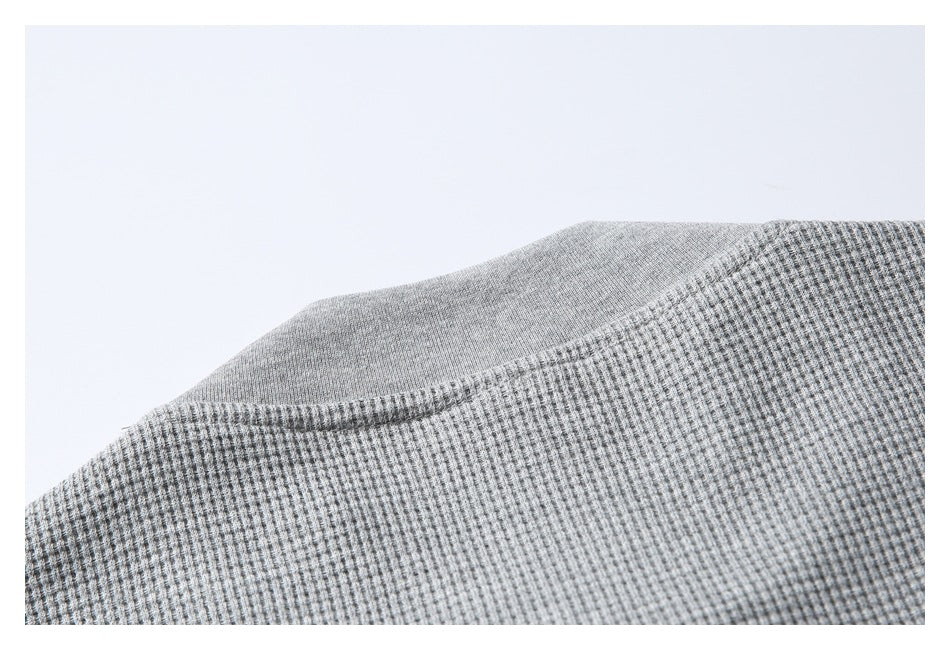 Close-up of the neckline seam on a gray textured garment.