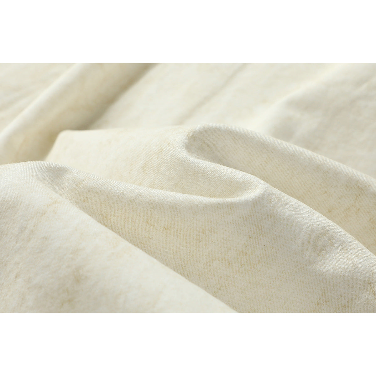 Close-up of softly textured, subtly mottled ivory shirt fabric draped in folds.