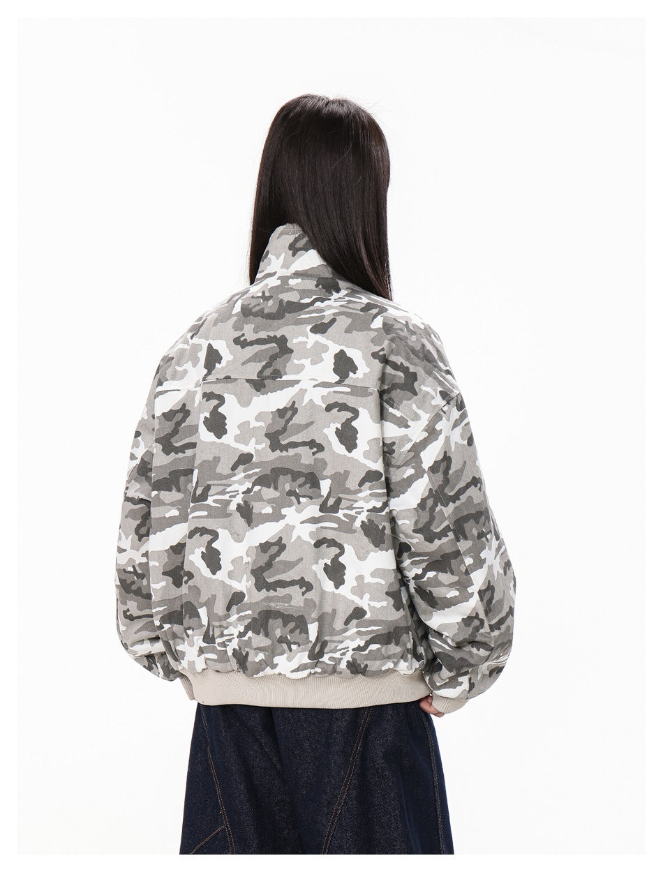 Back view of a person wearing a gray, white, and charcoal camouflage jacket with a beige ribbed hem.