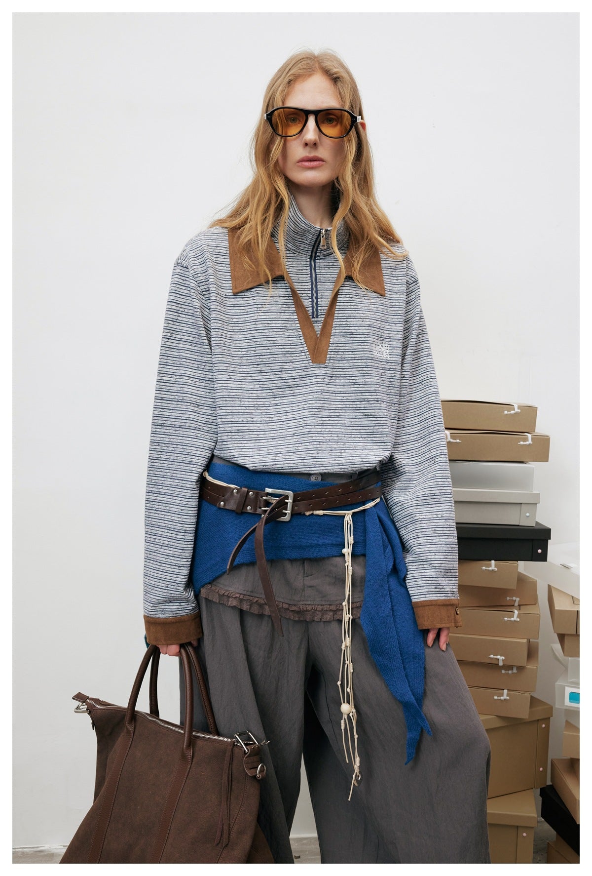 Model wearing the gray striped half-zip polo top with brown suede-look collar, layered with a belt and wide trousers