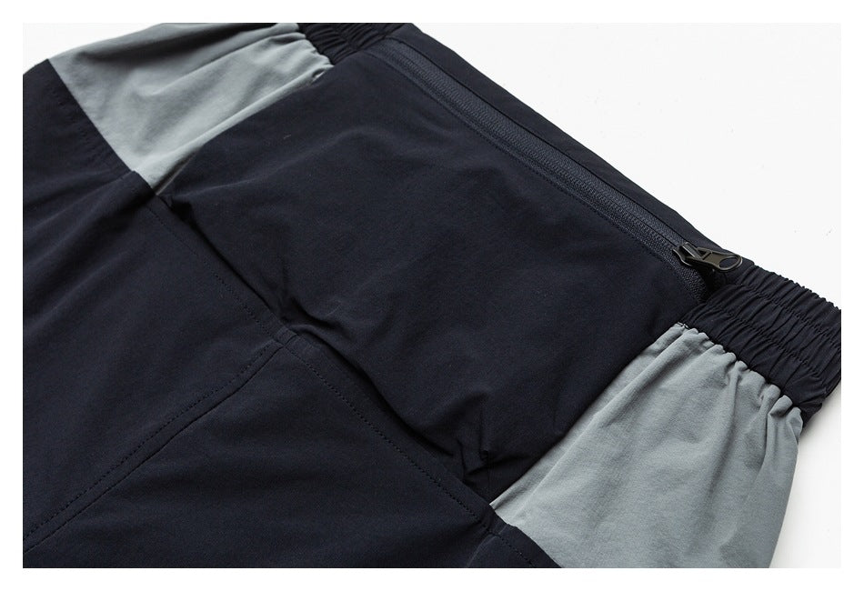 Close-up of black and gray color-blocked garment with a diagonal zipper and gathered black elastic edge.