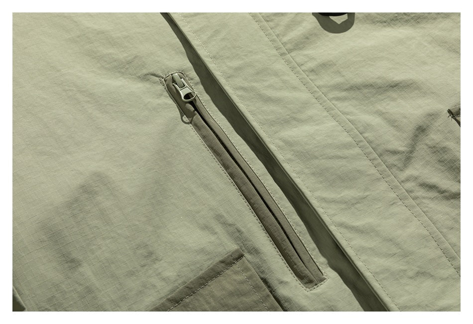Close-up of an olive-green jacket showing a diagonal zipper pocket and stitched panels.
