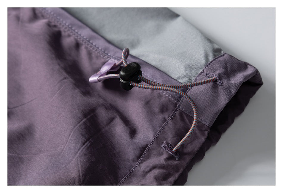 Close-up of purple shorts showing a multicolored elastic drawcord and black cord lock at the waistband.