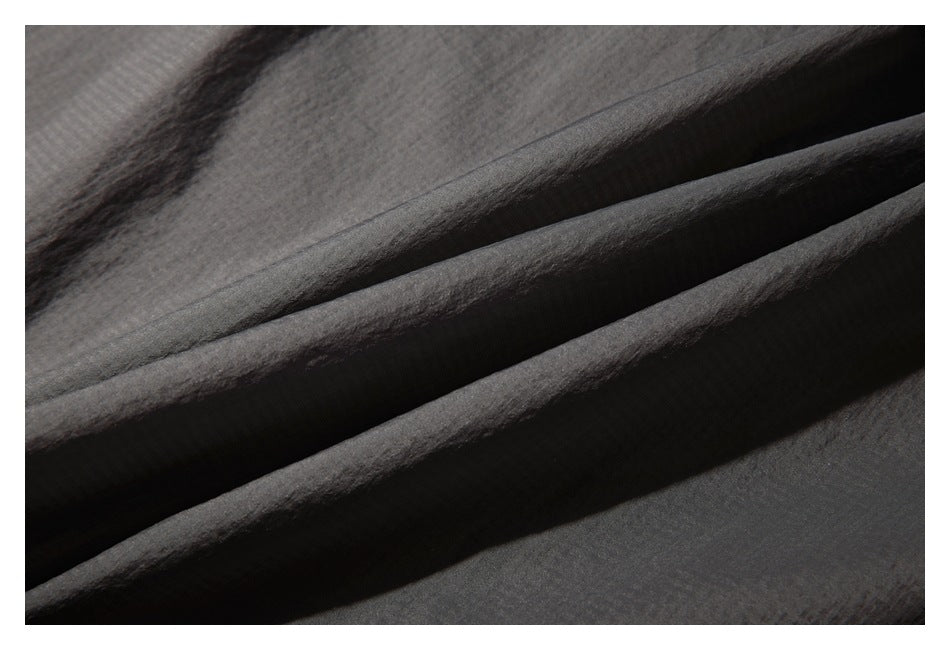 Close-up of dark charcoal fabric arranged in layered folds.