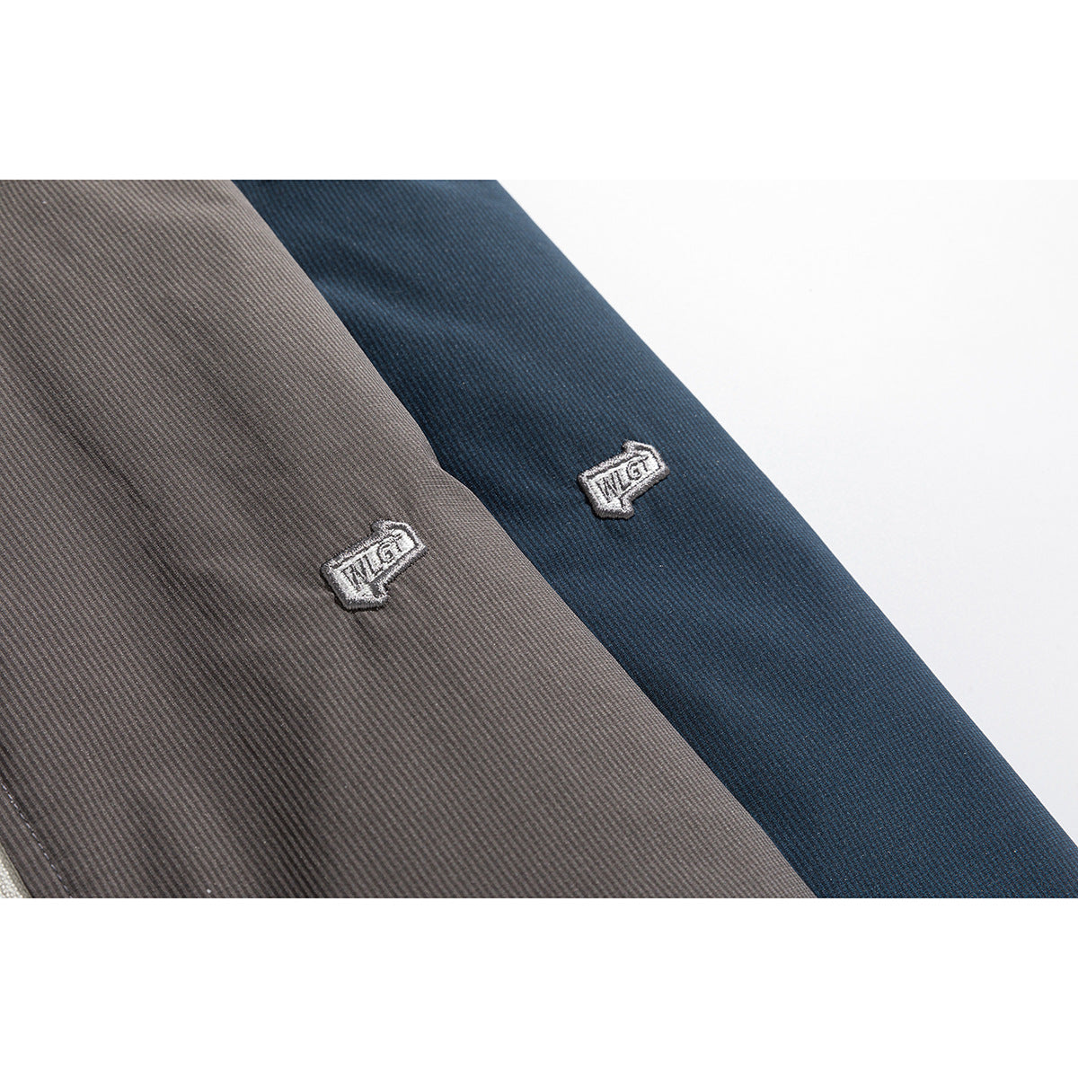 Close-up of embroidered emblems on charcoal and navy jacket fabric.