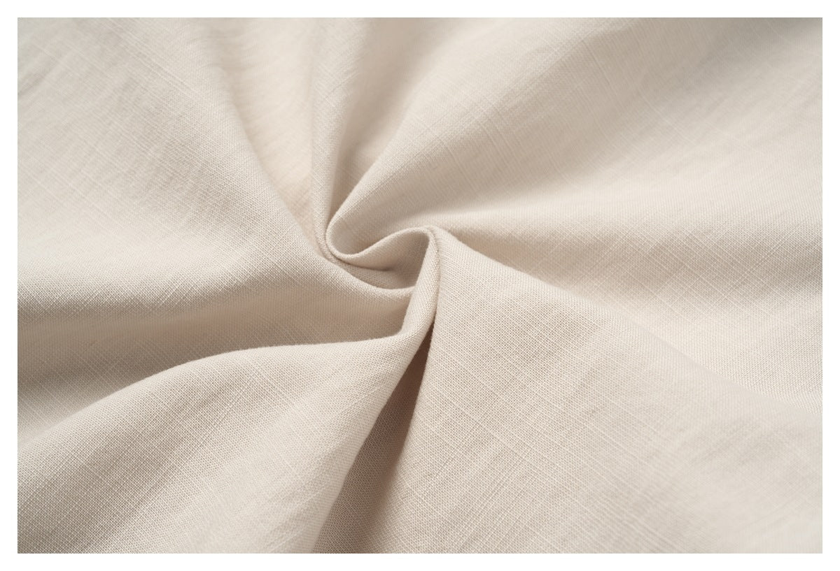 Close-up of light beige fabric draped into a spiral, showing its fine woven texture.