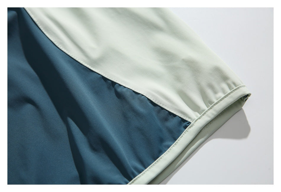 Close-up of the garment's pale mint sleeve panel, teal section, and stitched cuff.
