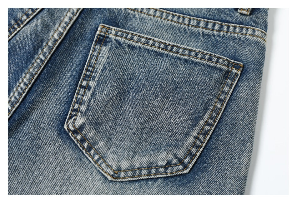 Close-up of a stitched back pocket on blue faded denim jeans.