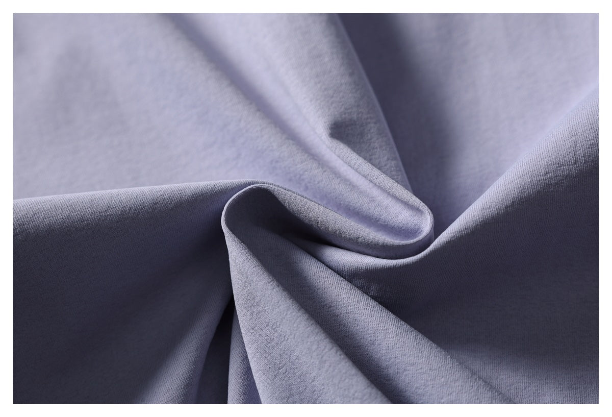 Close-up of plain lavender-gray fabric arranged in soft folds, showing its fine surface texture.