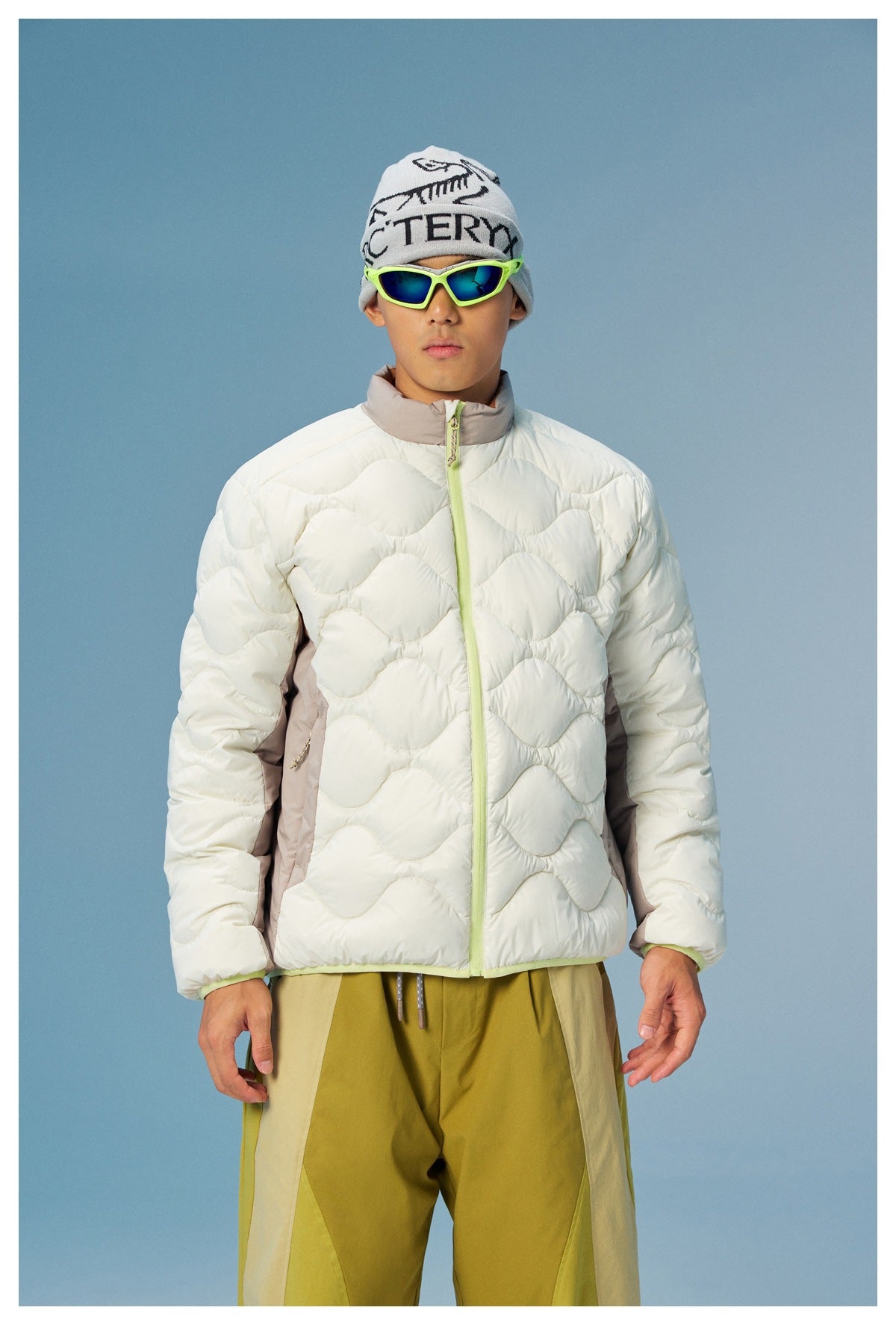 Front view of a model wearing a white wave-quilted jacket with taupe side panels and a lime-green zipper.