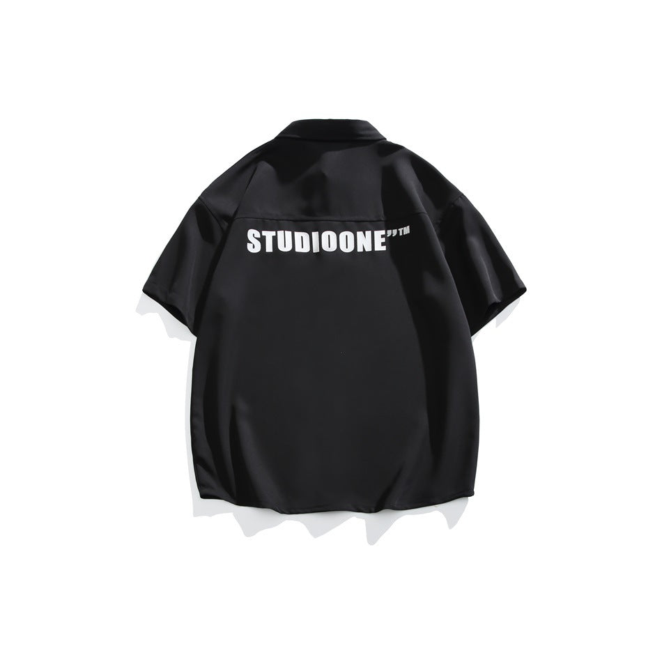 Back view of a black short-sleeve shirt with a large white block-letter print across the upper back
