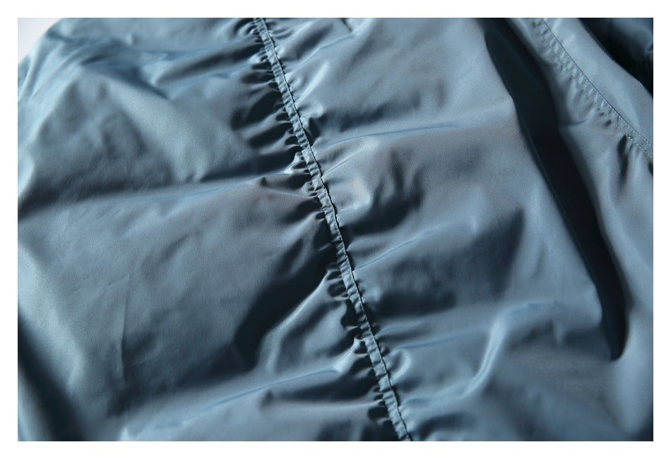 Close-up of a blue-gray jacket panel with a vertical stitched seam.