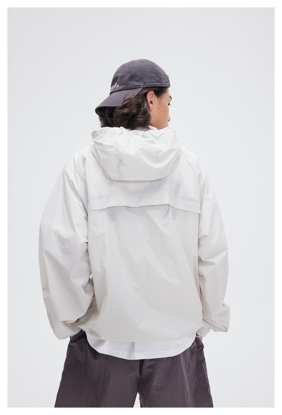 Back view of a model wearing a white hooded jacket with a back vent panel.
