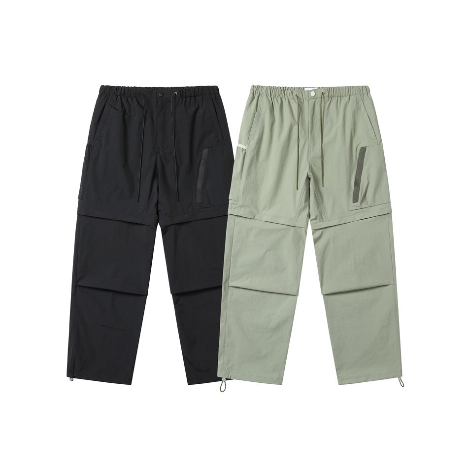 Front view of black and pale sage-green convertible cargo pants with drawcord waists and adjustable hems.