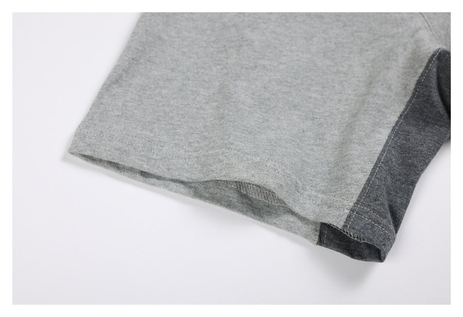 Close-up of a light gray sweatshirt sleeve hem with a dark charcoal contrast panel and visible stitching.