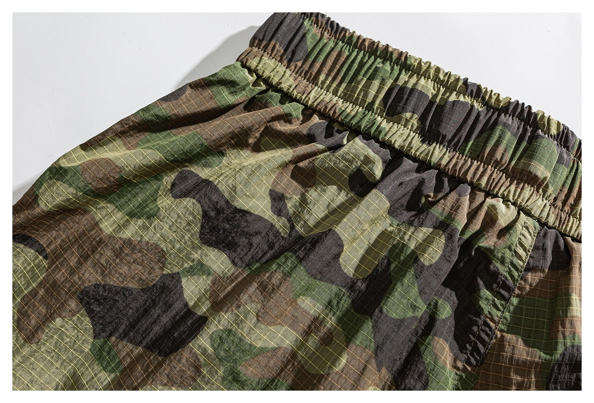 Close-up of camouflage shorts showing the wide gathered elastic waistband and grid-patterned fabric.
