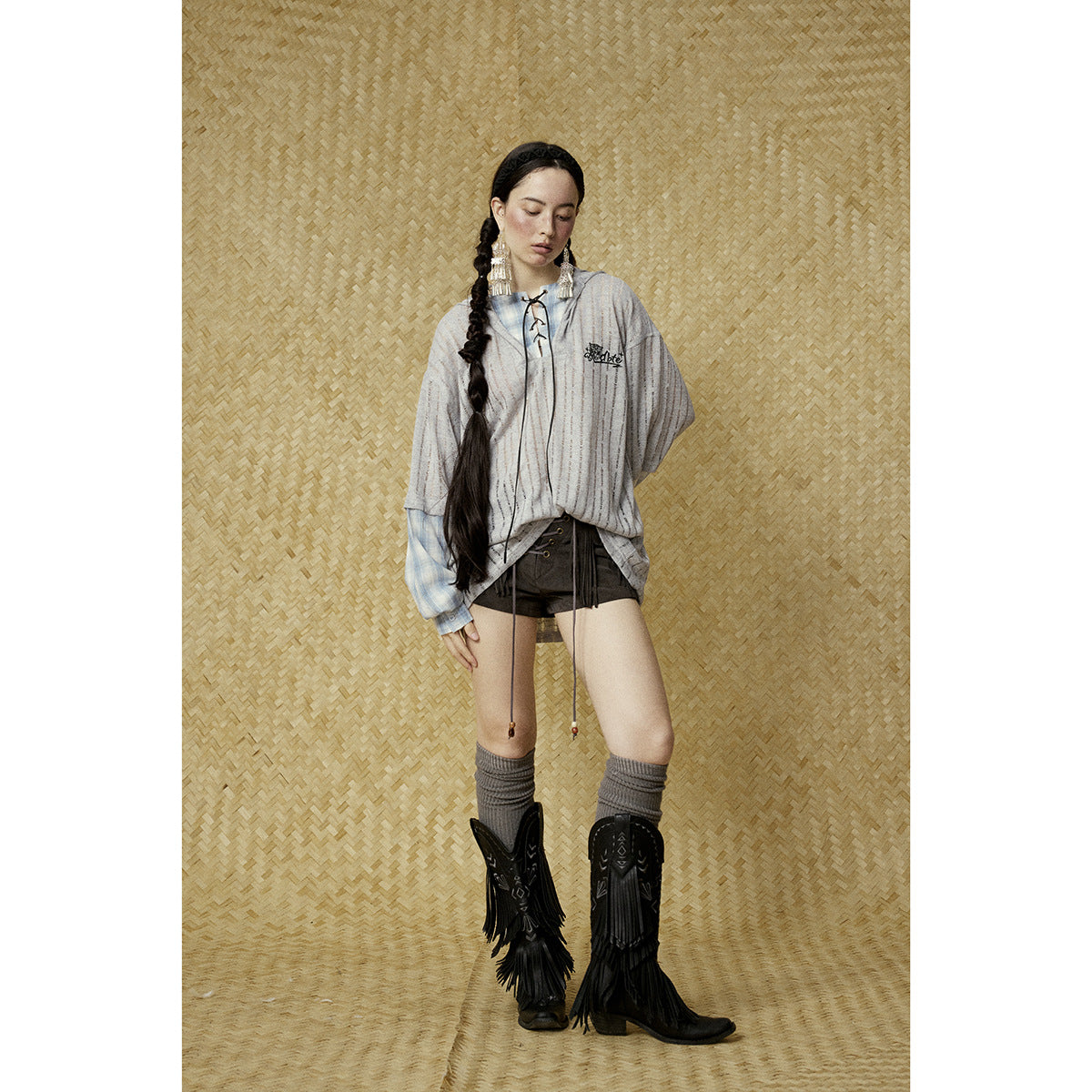 Full-length model wearing a gray striped hooded top with blue plaid sleeves and black lace-up shorts.