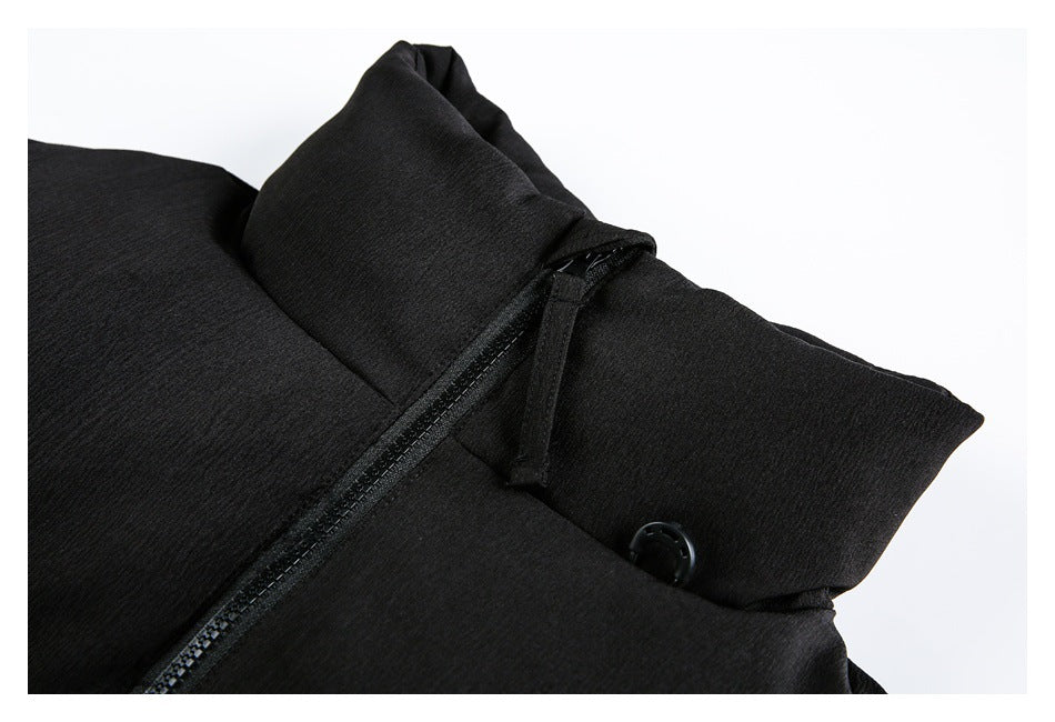 Close-up of a black padded jacket's high collar, front zipper and snap fastener.