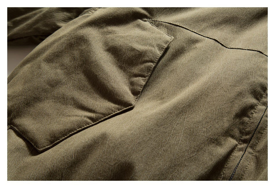 Close-up of an olive-brown jacket's flap pocket and surrounding stitching.