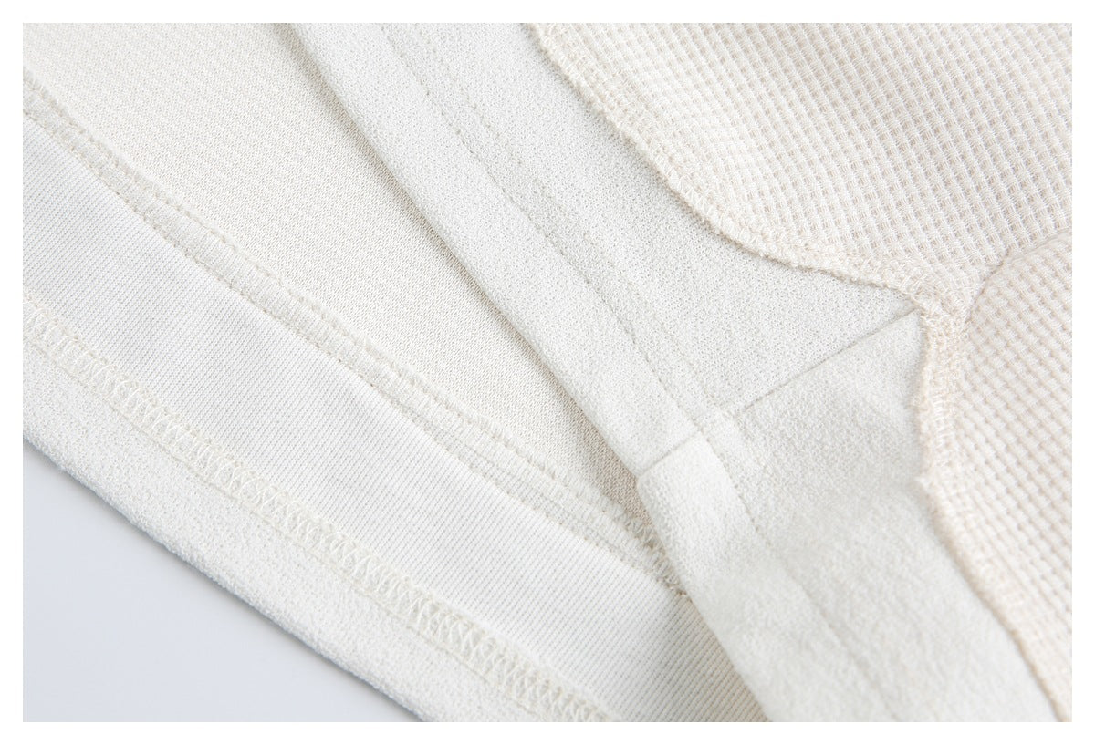 Close-up of an off-white garment's interior seam and overlocked stitching.