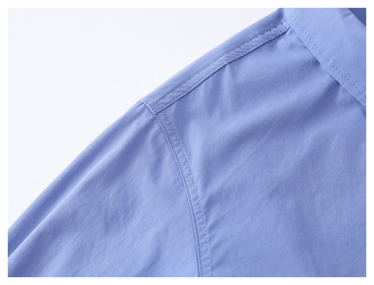 Close-up of a light blue shirt shoulder seam and collar edge.