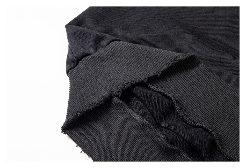 Close-up of a black ribbed garment edge with a folded seam and frayed finish.