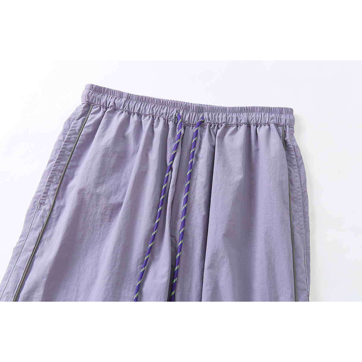 Close-up of lavender-gray pants with an elastic waistband, purple patterned drawcords, and narrow side piping.