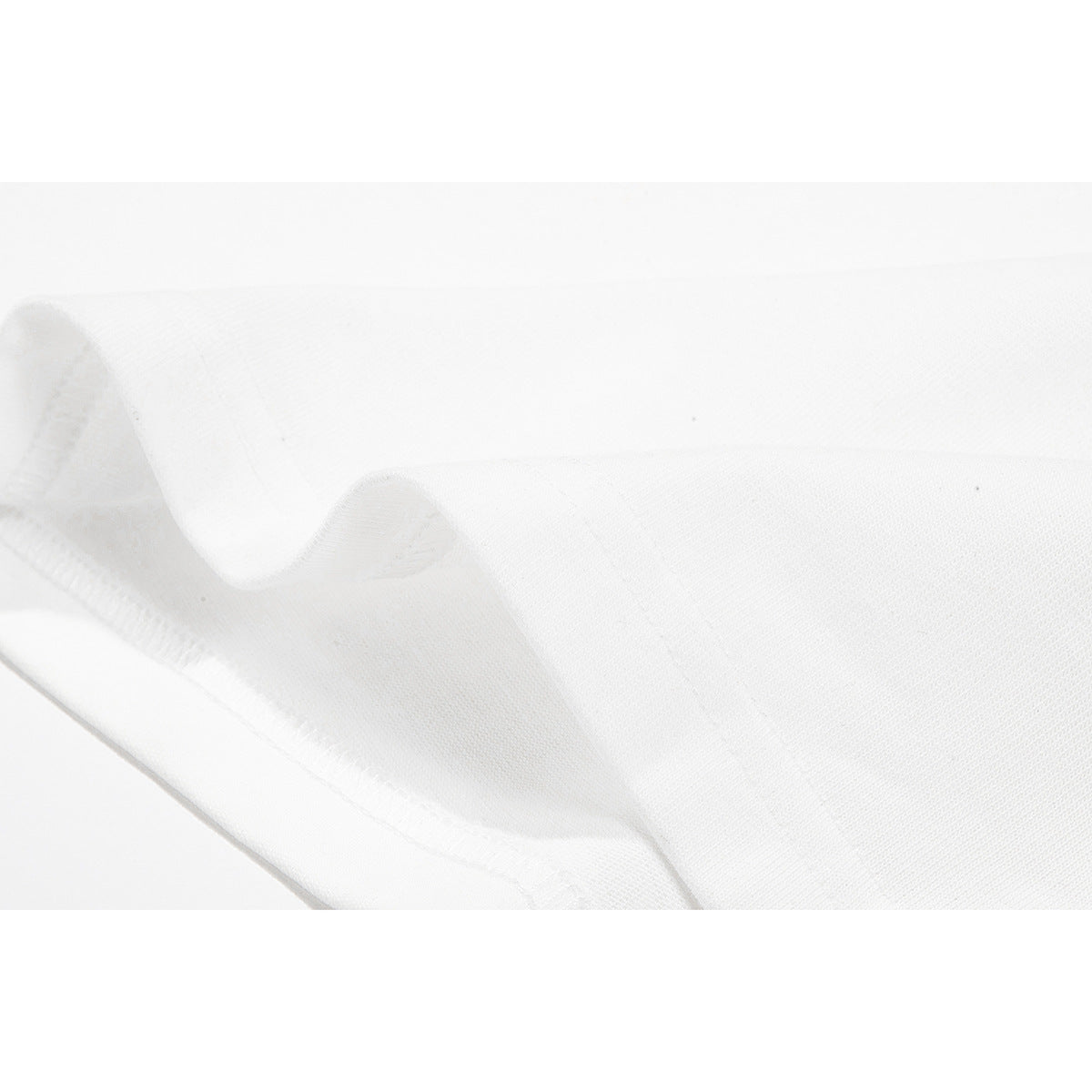 Close-up of white T-shirt fabric folded to show a stitched edge and hem.